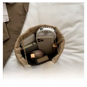 Interno spazioso della borsa trapuntata beige con smartphone e articoli da trucco