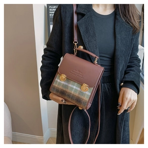 Dettaglio borsa vintage a quadri con patta in pelle marrone e fibbie in metallo oro