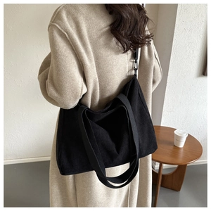 Detail of black corduroy tote bag showing soft texture and wide canvas shoulder straps