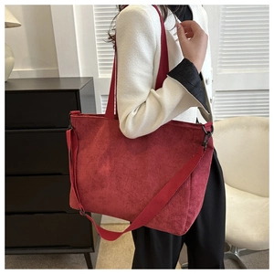 Detail of red corduroy tote bag showing striped texture and detachable shoulder strap