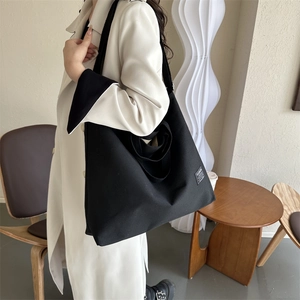 Large black canvas tote bag with adjustable shoulder strap and fashion label for women