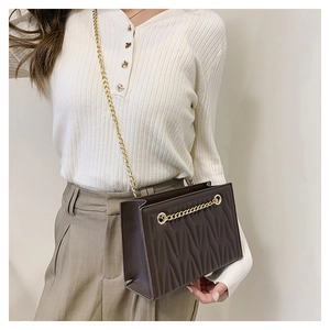 Detail of dark brown quilted crossbody bag with gold chain and pleated texture