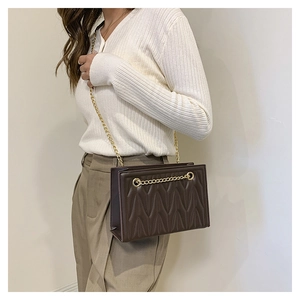 Close-up of brown quilted faux leather bag with V-shaped stitching and golden chain strap