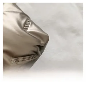 Detail der champagnergoldenen Stepptasche mit feiner Textur und horizontalen Nähten