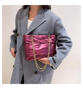 Detail of metallic purple quilted tote bag featuring gold chain straps and puffer texture