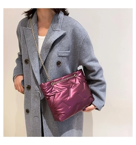 Detail einer tiefvioletten gesteppten Puffertasche mit Metallic-Finish und Goldkette