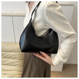 Détail du sac hobo en cuir PU noir avec lettrage embossé sur fond intérieur minimaliste