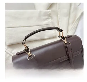 Detail view of the golden metal hook and handle on the dark brown vintage leather backpack