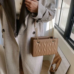 Brown quilted leather chain crossbody bag with V-shaped stitching and golden strap