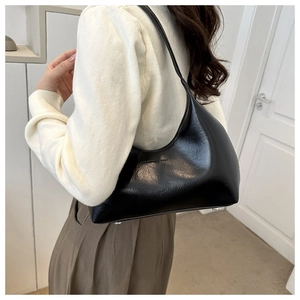 Gros plan d'un sac hobo noir brillant en similicuir avec des clous de protection métalliques