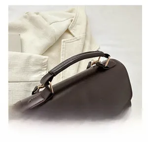 Close-up of a vintage dark brown leather backpack handle and golden metal buckle