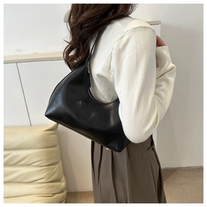 Gros plan sur un sac hobo noir minimaliste avec fermeture éclair et détail de logo