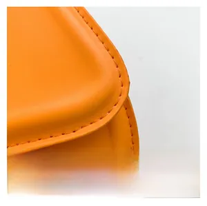 Detailed close-up of bright orange leather texture and fine stitching on the saddle bag