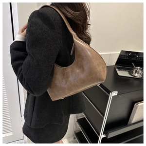Gros plan d'un sac sous les bras en cuir marron vintage avec une veste élégante.