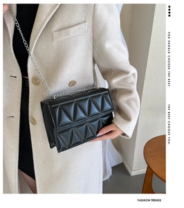 Detail of black quilted shoulder bag with geometric patterns and silver chain strap