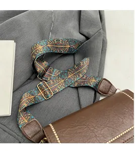 Detail of adjustable geometric woven strap on brown textured leather crossbody bag