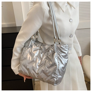Sac fourre-tout matelassé argenté avec finition métallique porté dans un décor moderne