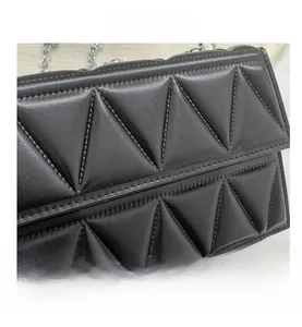 Detailed view of black triangular quilted texture and premium silver metal chain strap