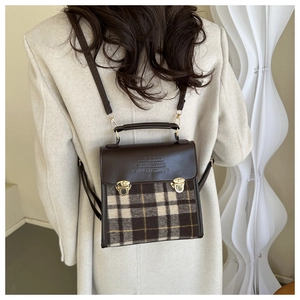 Detail view of the vintage brown plaid backpack with metal clasp and leather handle