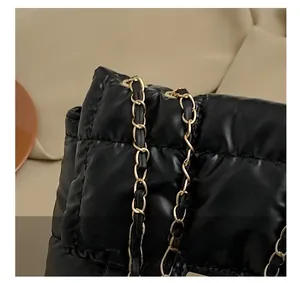 Close-up of black quilted shoulder bag featuring premium gold metal chain hardware detail