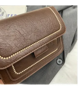 Detail of dark brown vintage shoulder bag showing textured leather and gold floral studs