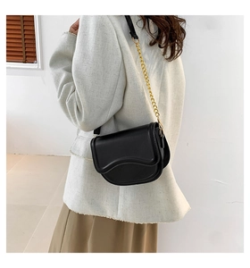 Side view of a black saddle crossbody bag with gold metal chain and leather strap