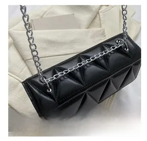 Close-up of geometric quilted leather textures and silver metal chain links on a chic black bag