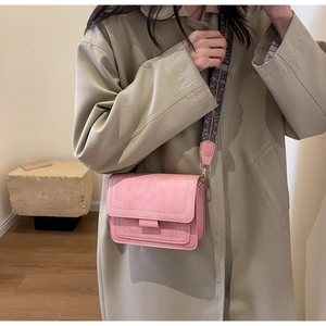 Close-up of pink crossbody bag with a wide ethnic style patterned woven strap and matte finish