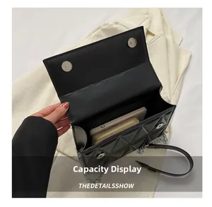 Detail showing internal capacity for phone and wallet in black quilted chain crossbody bag