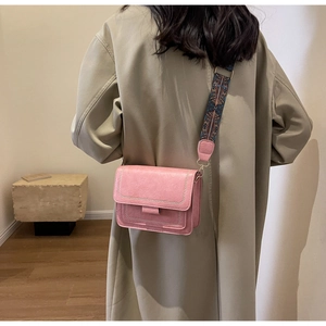 Detailed shot of pink leather crossbody bag with geometric pattern wide shoulder strap