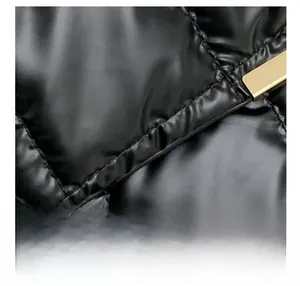 Detailed close-up of glossy black quilted fabric with elegant gold metal accent