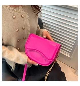 Detailed view of rose pink saddle bag featuring wave-edge flap and glossy patent leather finish
