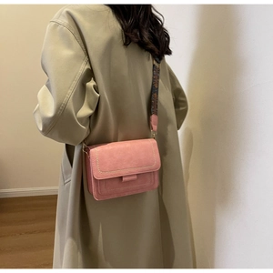 Detail of pink faux leather crossbody bag with ethnic style wide shoulder strap on a model