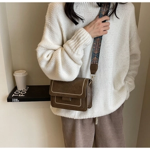 Detail of vintage brown leather crossbody bag with ethnic patterned strap and contrast stitching