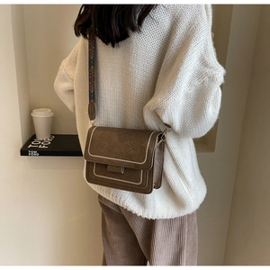 Detail of vintage brown crossbody bag featuring ethnic pattern wide strap and white stitching