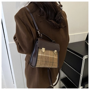 Detail of vintage plaid wool and brown leather backpack with golden buckles