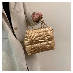 Detail of gold quilted handbag featuring chain handles and premium metallic texture