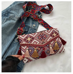 Detail of colorful woven shoulder strap with vibrant tassels on a crossbody envelope bag