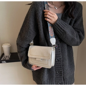 Detail of off-white crossbody bag with ethnic print strap and contrast stitching