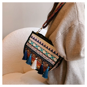Detalle de bolso bandolera bohemio con motivos étnicos y adornos de borlas de colores