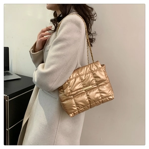 Detail of champagne gold quilted shoulder bag with metallic finish and chain strap