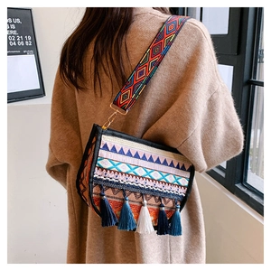 Detalle de bolso bohemio con bordado étnico, borlas coloridas y correa ancha tejida