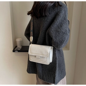 Detailed view of white pleated leather texture and wide jacquard strap on crossbody bag