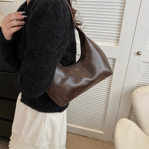Sac hobo rétro en cuir marron avec texte embossé porté par un mannequin dans un décor épuré