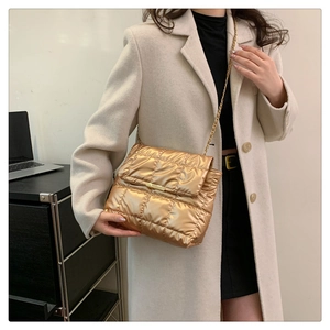 Detail of gold quilted shoulder bag with chain strap styled with a beige coat