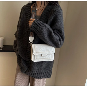 Detailed close-up of a white flap crossbody bag featuring a colorful ethnic patterned wide strap