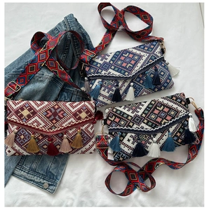 Vintage knit messenger bag with tassel trim and geometric patterns on a wide strap