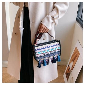 Detalle de bolso bohemio de lona con bordados geométricos coloridos y borlas azules