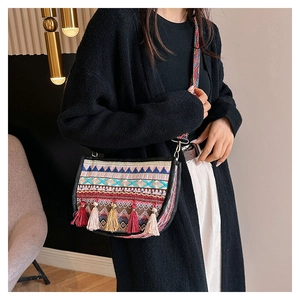 Detalle del bolso bandolera étnico con bordado bohemio y borlas de colores en modelo