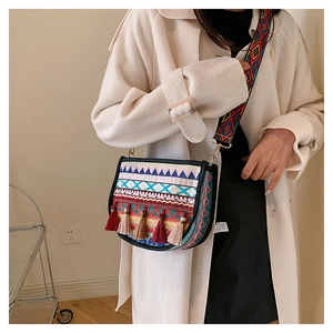 Detalle de bordado bohemio y borlas de colores en un bolso bandolera tipo montura